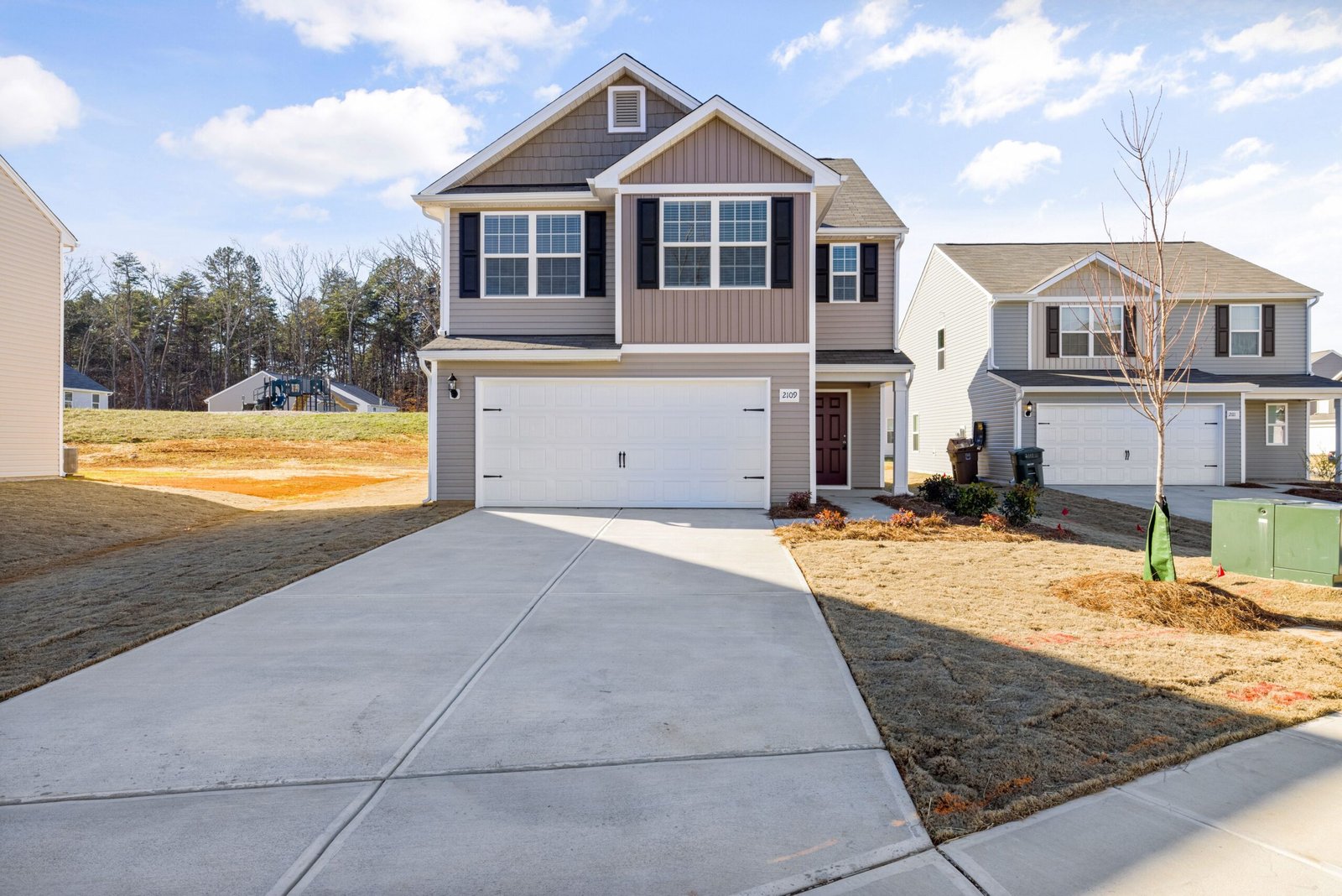 Contemporary suburban house with a wide driveway and landscaped front yard.